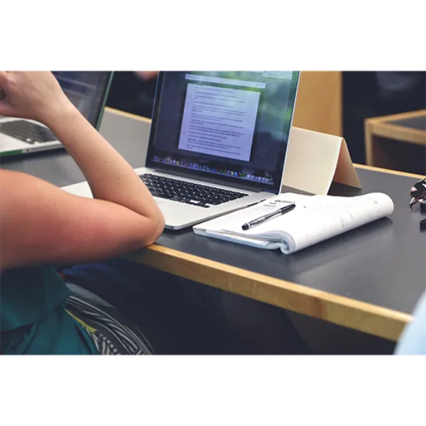 Computador portátil com documentos e caneta em mesa de escritório, foco em parcerias B2B da SuoViaggio.
